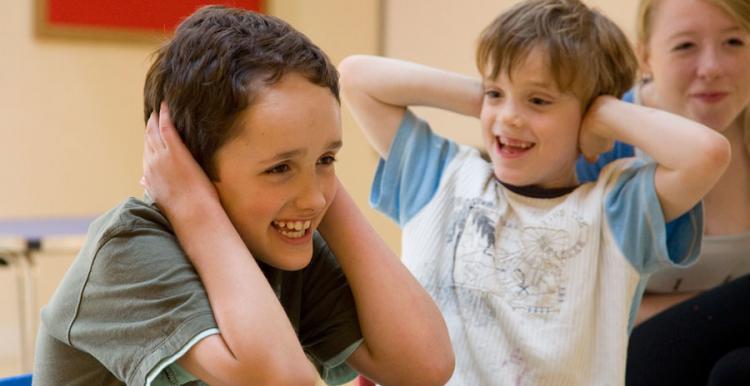 two children laughing with hands on ears