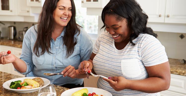 two women talking and eating a healthy meal 