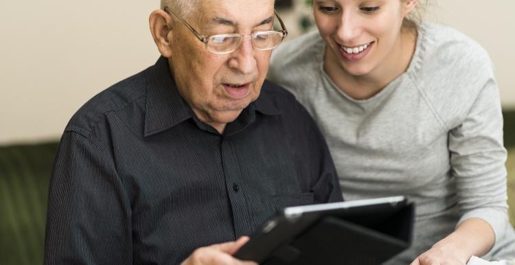 an-old-man-sat-with-a-younger-woman-looking-at-ipad