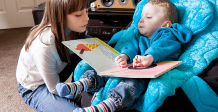 young child and baby looking at a book together 