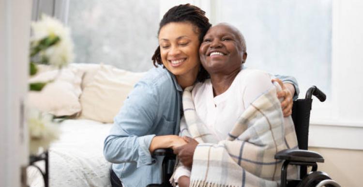 a woman in a wheelchair with her carer smiling 