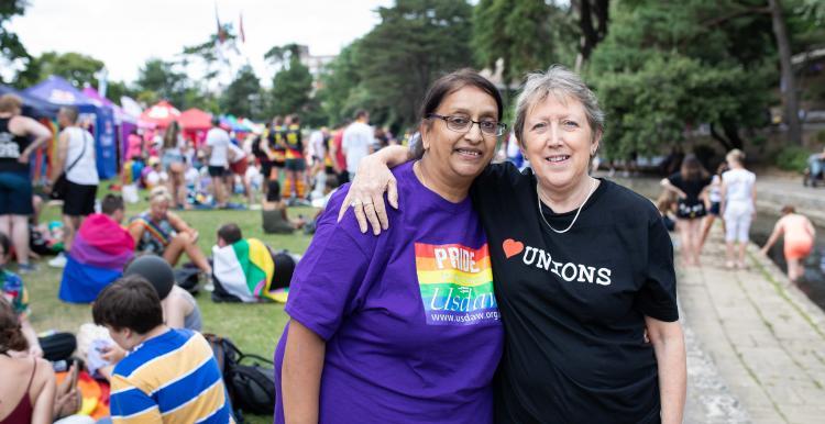 Two people at a pride event with their arms around each other 