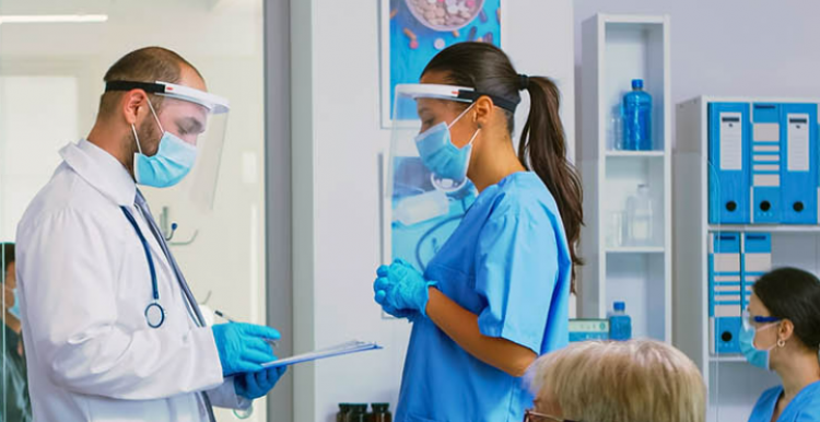 Doctor with clipboard talking to young woman wearing PPE