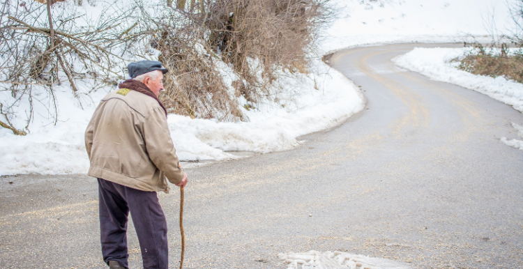 Older man outside walking in the snow 