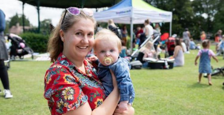 woman holding a baby at a Healthwatch outdoor event 