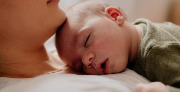 Women with baby lying down on her chest.