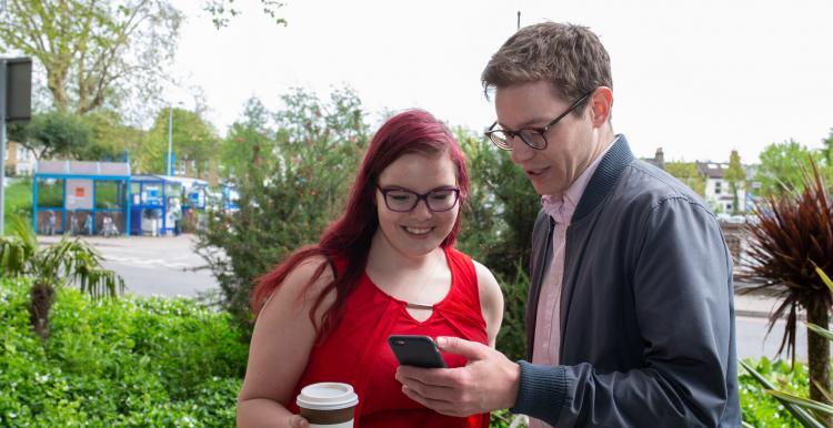 A man and a woman looking at a mobile phone 