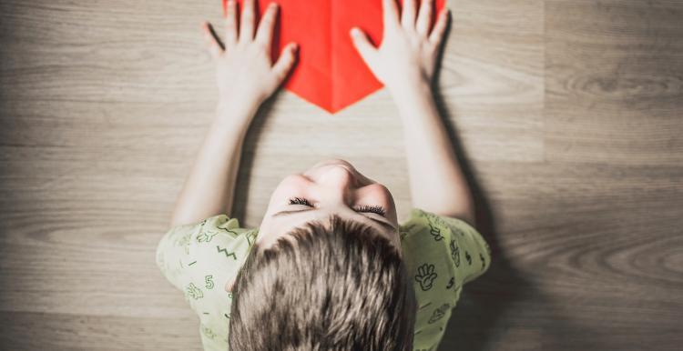 young child with hands on a paper heart 