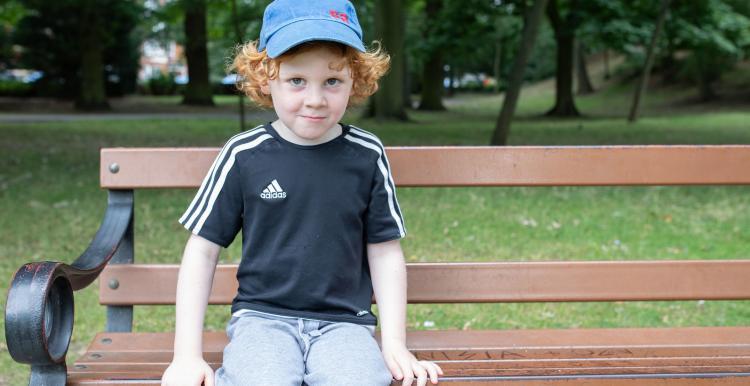 young child sat on a bench 