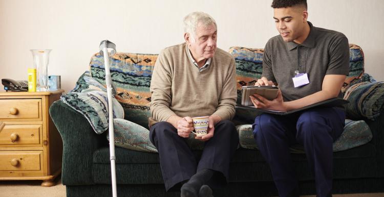 Older gengleman and healthcare assistant looking at an ipad