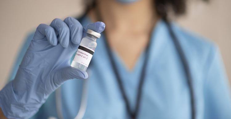 Photograph of a medical professional holding a vial of vaccine