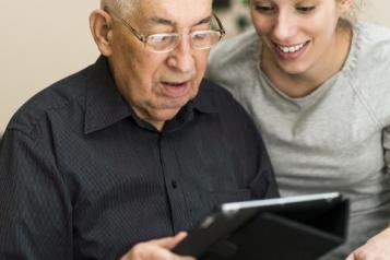 an-old-man-sat-with-a-younger-woman-looking-at-ipad