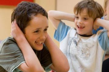 two children laughing with hands on ears