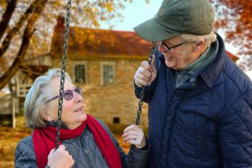 Lady sat on a swing with man pushing 