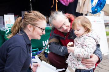 Healthwatch staff member talking to older man with child 