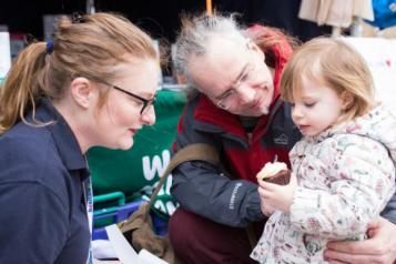 Healthwatch staff member taking to man and young child 