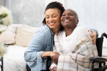 a woman in a wheelchair with her carer smiling 