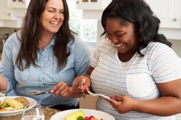 two women talking and eating a healthy meal 