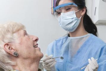 Older lady in a dentist chair smiling at the dentist