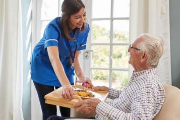 healthcare assistant and an older man in a chair 