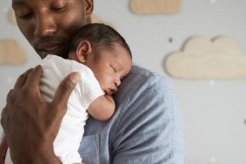 Safer-Sleep-Week man holding young baby 