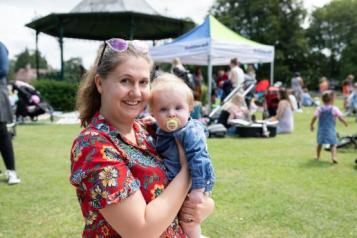 woman holding a baby at a Healthwatch outdoor event 