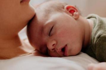 Women with baby lying down on her chest.