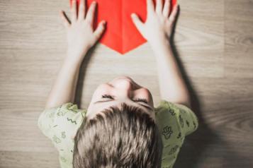 young child with hands on a paper heart 
