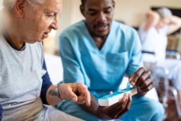 nurse_sitting_on_bed_and_giving_instructions_to_senior_patient