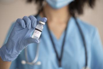 Photograph of a medical professional holding a vial of vaccine